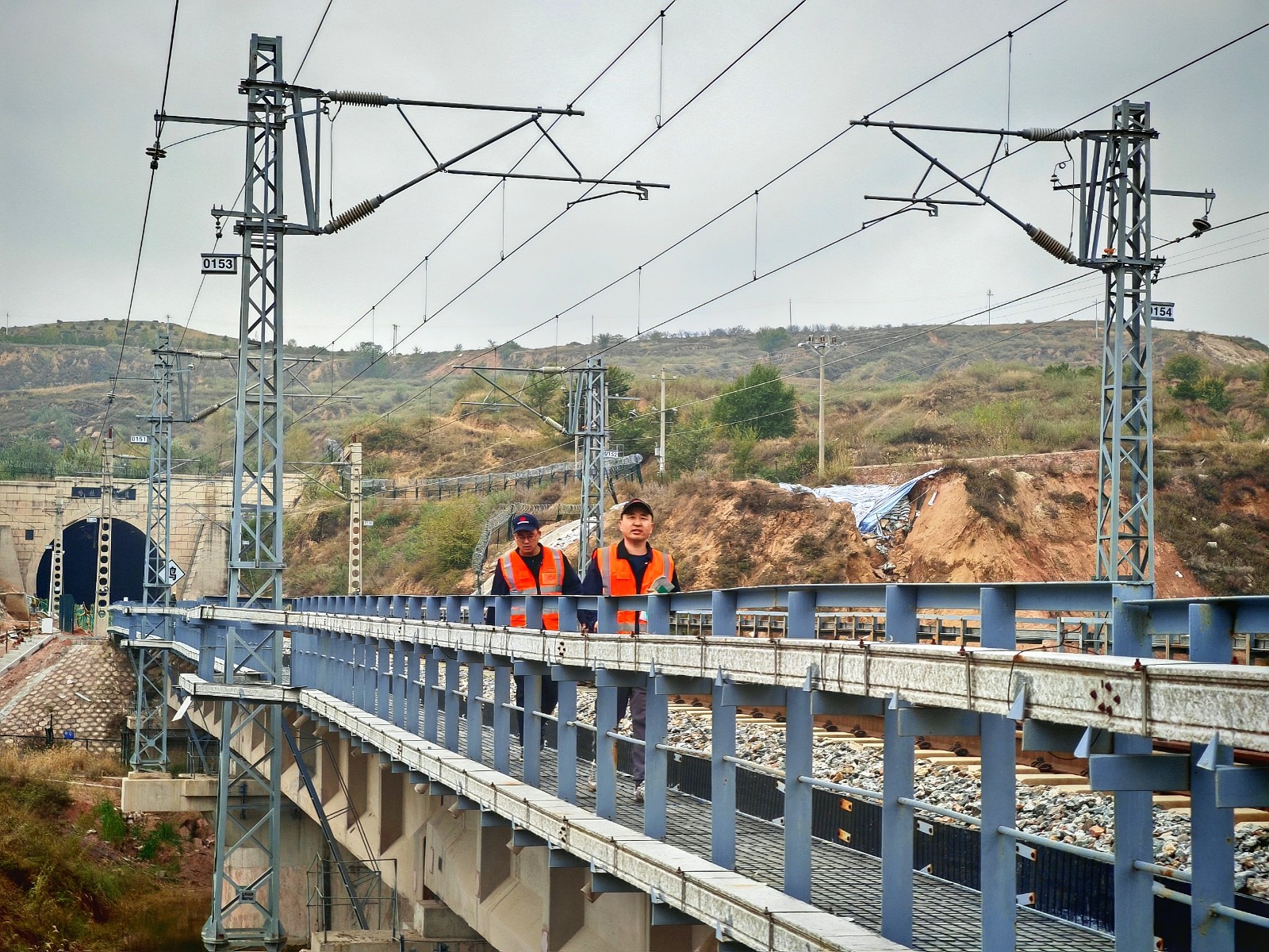 图为应急小组人员徒步通过隧道后在铁路桥上排查应急线路